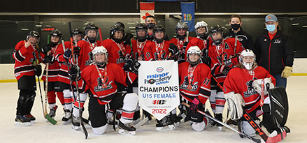 Image of girl’s hockey team posing with championship banner.