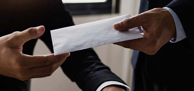 Two hands exchanging a white envelope