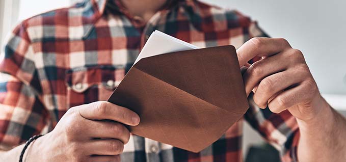 Person with brown envelope reading a piece of paper