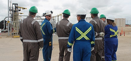 Group of people with hard hats at a loading rack.